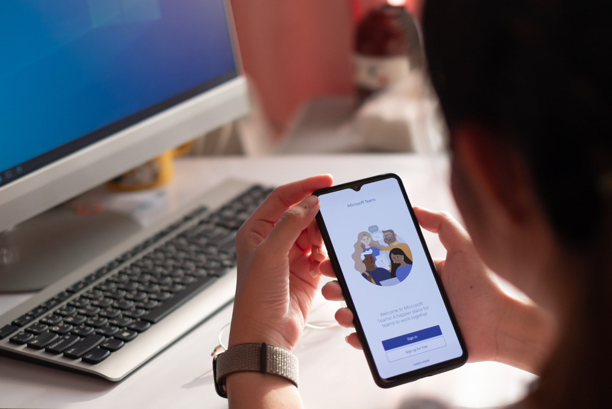 A person holding a smartphone displaying the Microsoft Teams application.